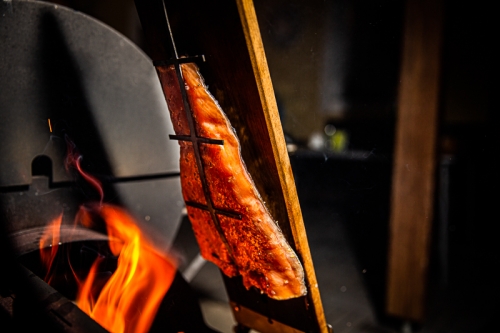 Lachs von der Planke über dem offenen Grill wo Flammen herauskommen